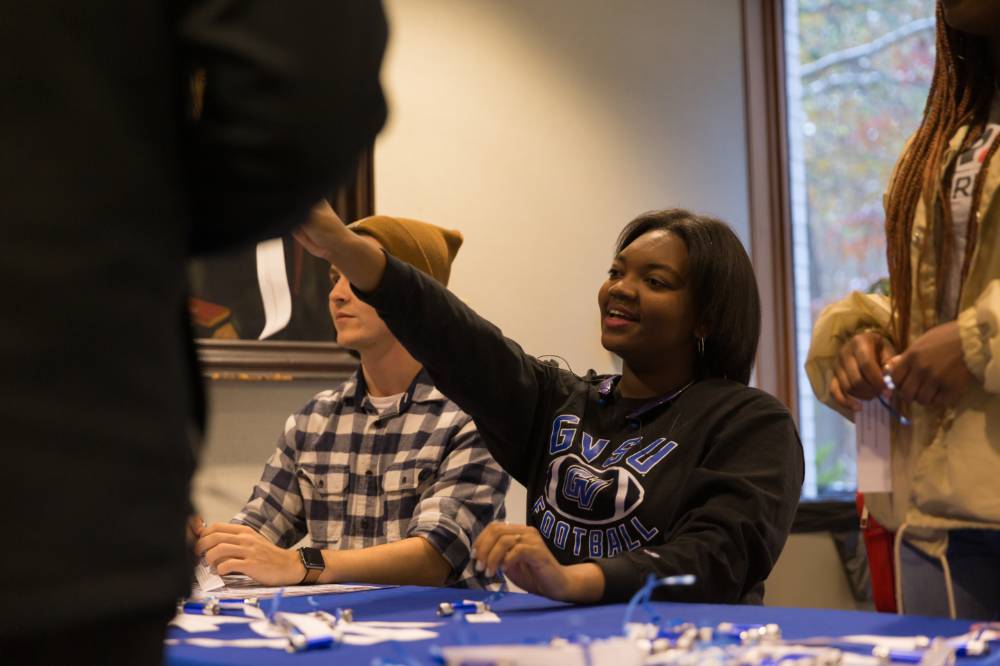 Image of student workers passing out first gen day goodies at sign in table